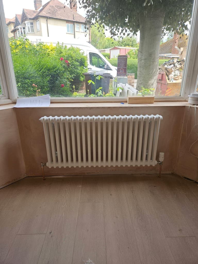 White column radiator installed under a bay window