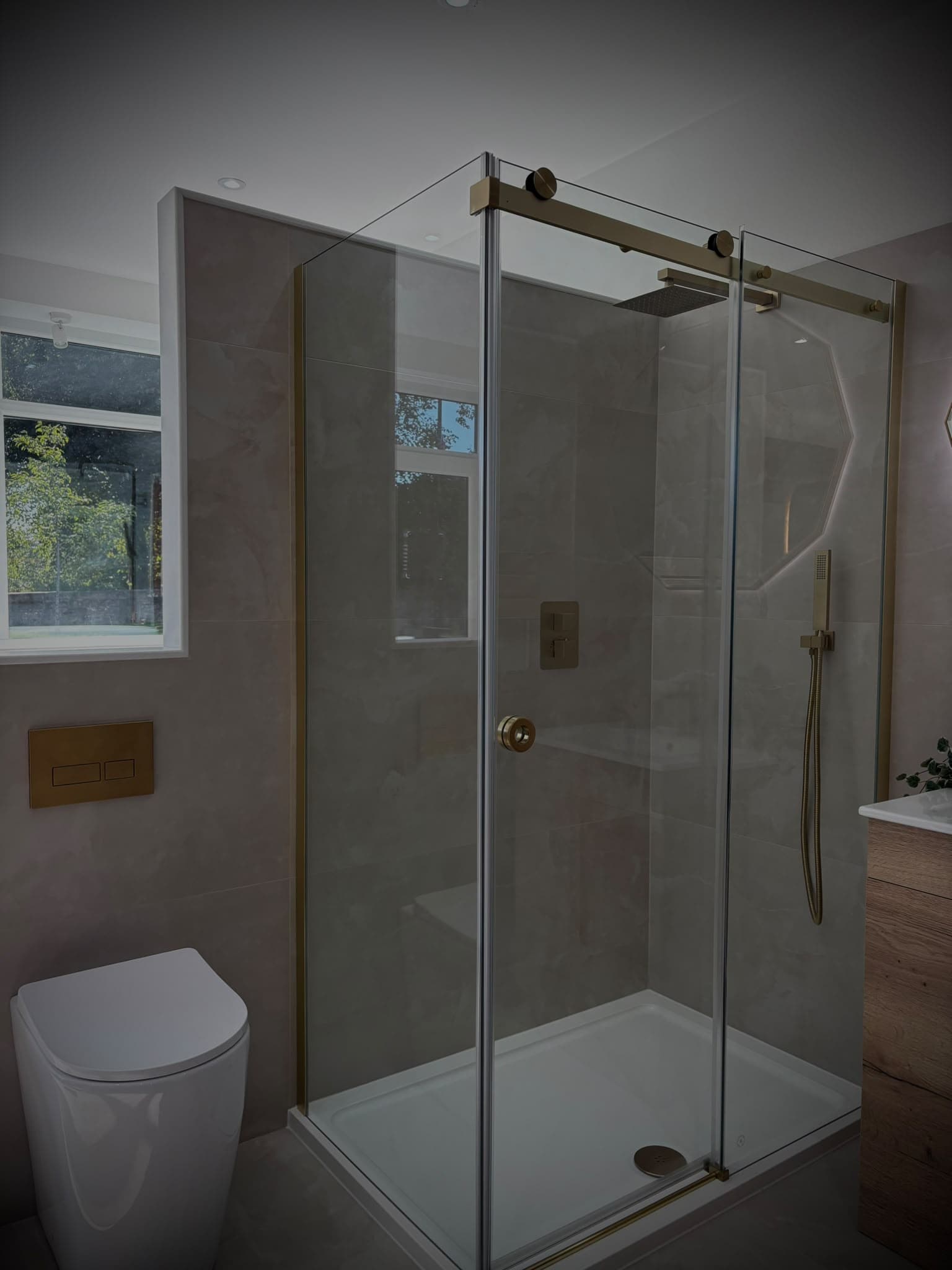Frameless sliding shower enclosure with brushed brass hardware and concealed thermostatic valve