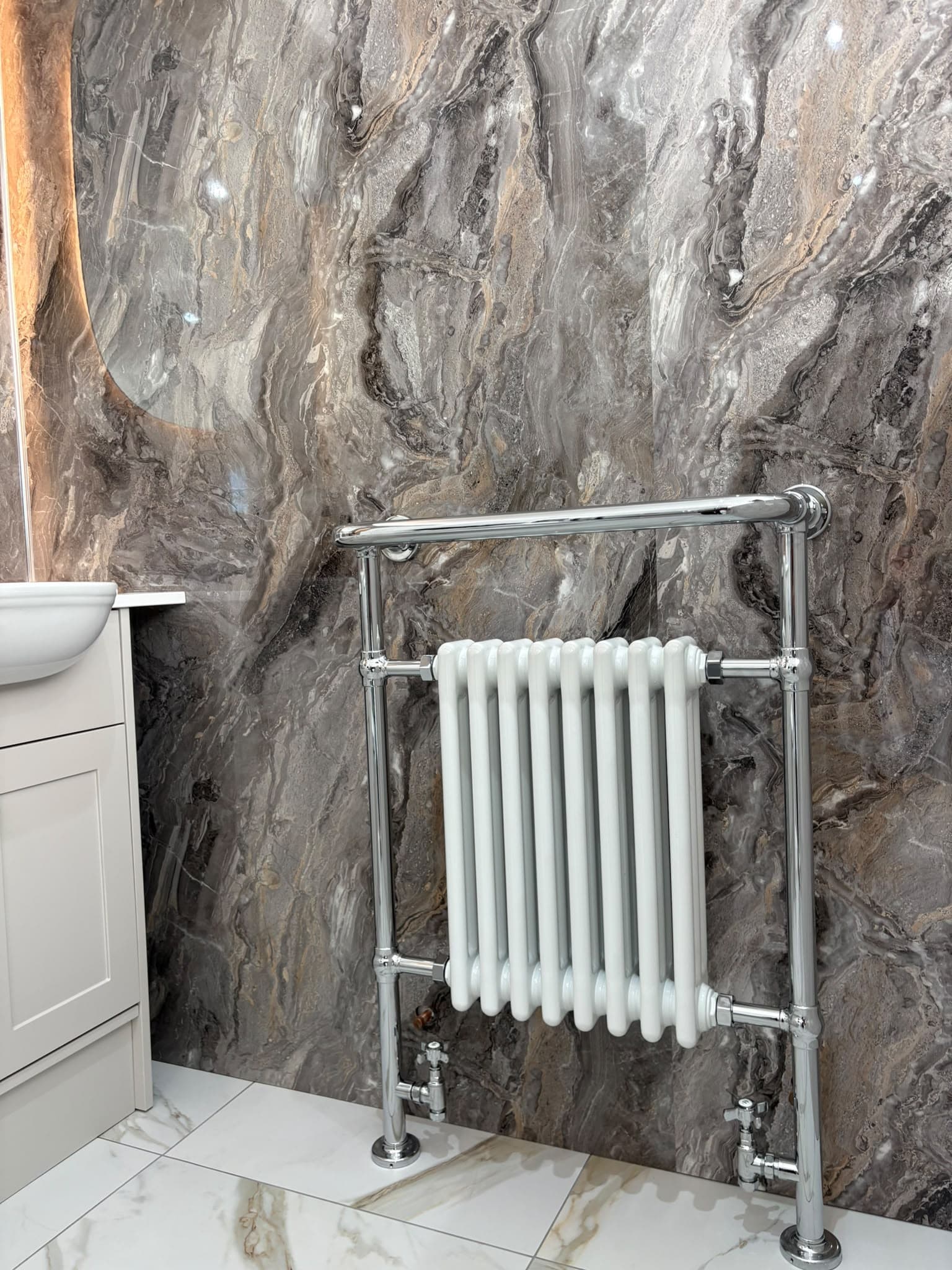 Chrome traditional towel radiator against dark marble-effect wall panels