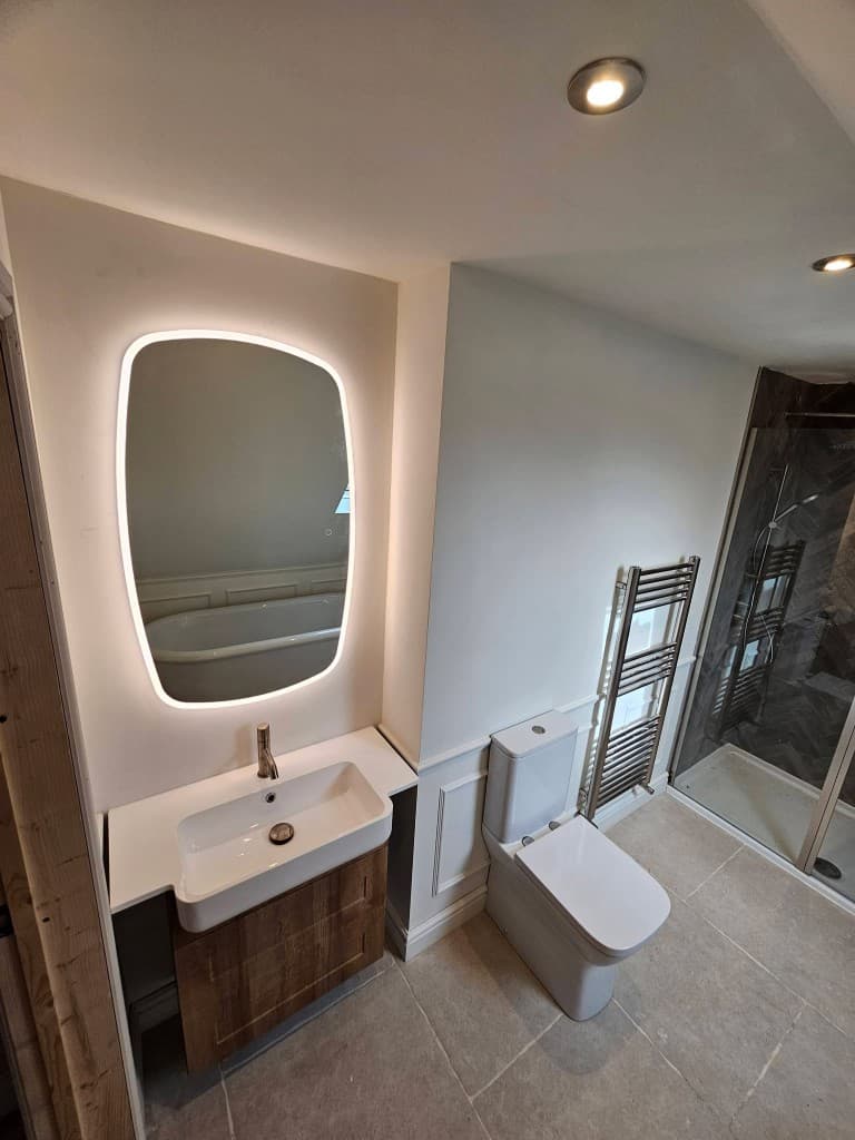 Herringbone tile shower with backlit mirror